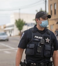 a police officer wearing a face mask walks down the street