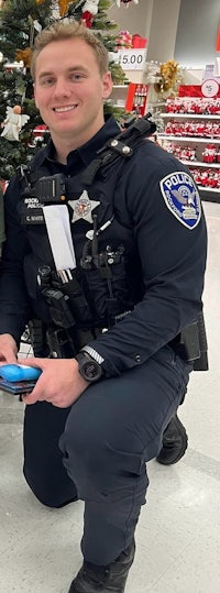 two police officers posing in front of a christmas tree