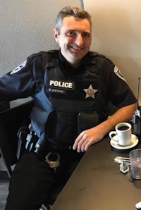 a police officer sitting at a table with a cup of coffee