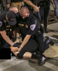 a group of police officers are holding a man on the ground